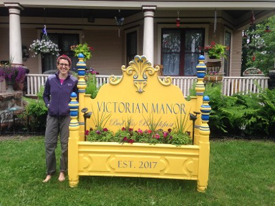 Customer Smiling Next to Victorian Manor Sign